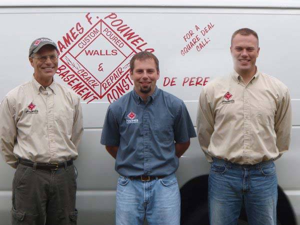three men standing in front of work truck smiling